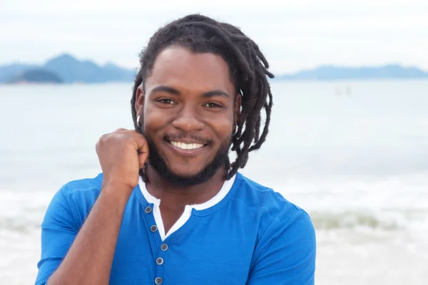 Смеющийся африканский американец с дредами на пляже — стоковое фото