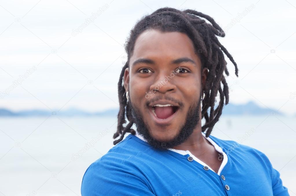 Happy african american guy with dreadlocks at beach