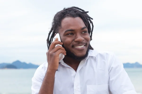 Chico afroamericano con rastas y camisa blanca en el teléfono — Foto de Stock