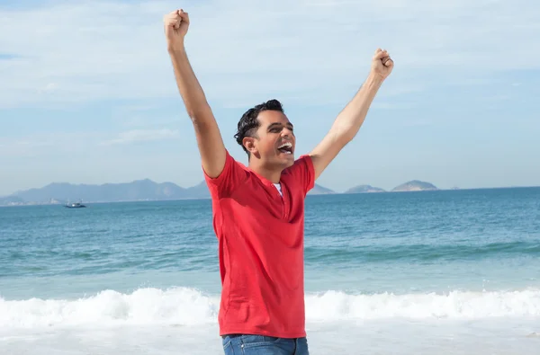 Смеющийся латиноамериканец аплодирует на пляже — стоковое фото