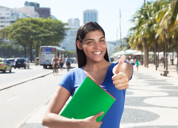 Latin student med långa mörka hår i staden visar tummen — Stockfoto