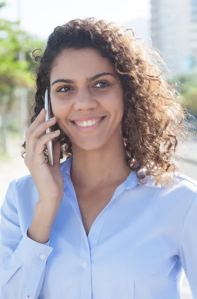 Laughing latin woman with blue blouse at phone in the city — Stock Fotó