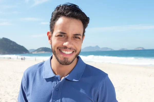 Schöner Typ mit Bart und blauem Hemd am Strand — Stockfoto