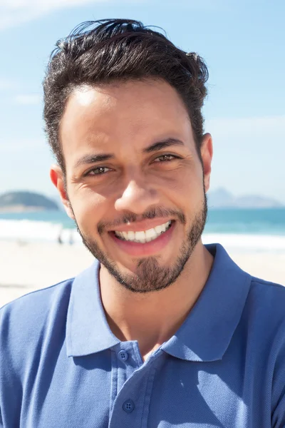 Portrait of a guy with beard and blue shirt at beach — Stock fotografie