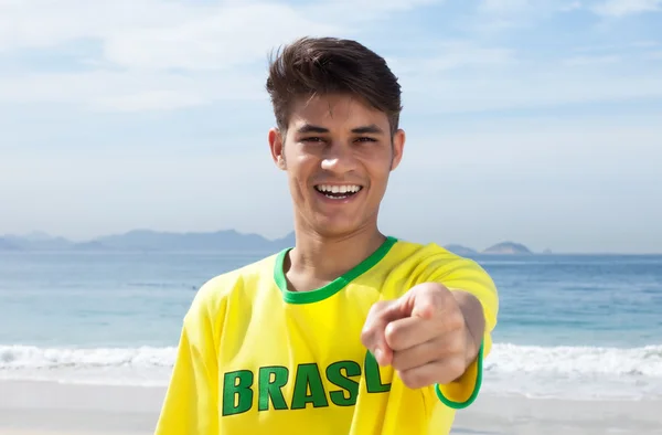 Brazilian sports fan at beach pointing at camera — Stock Photo, Image