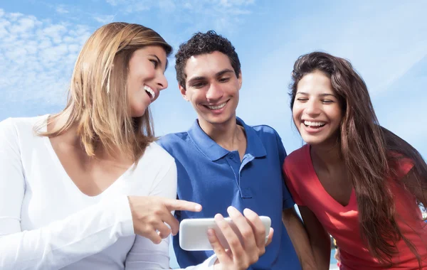 Grupo de jóvenes mostrando en las fotos en el teléfono inteligente — Foto de Stock