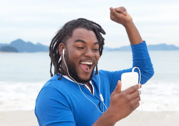 African american guy with dreadlocks listening to music at beach — Stock Photo, Image