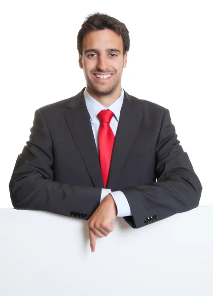 Apontando homem de negócios hispânico com terno e placa branca — Fotografia de Stock