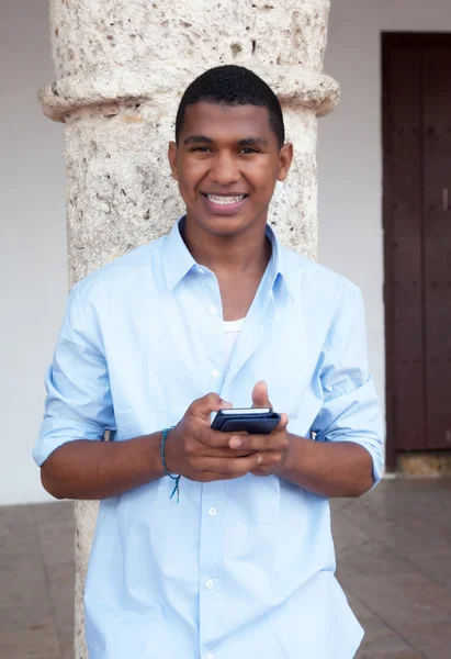 Chico joven en una camisa azul escribiendo mensaje en el teléfono — Foto de Stock