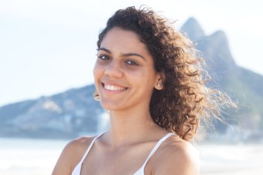 Rio de Janeiro kumsalda kıvırcık saçlı Latin kadın gülüyorsun