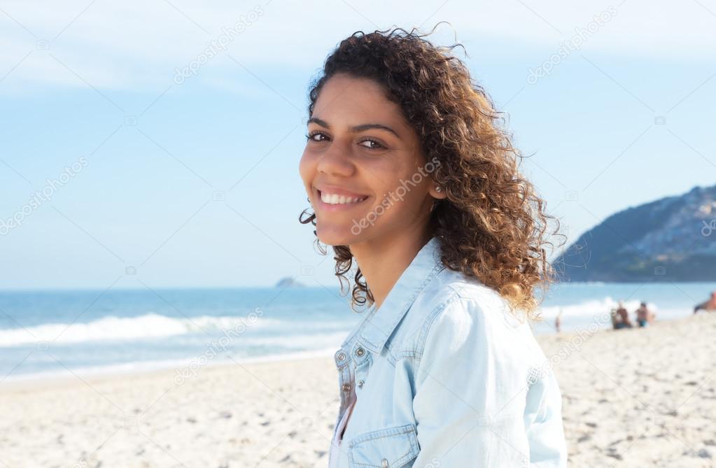 Laughing latin woman with curly hair at beach