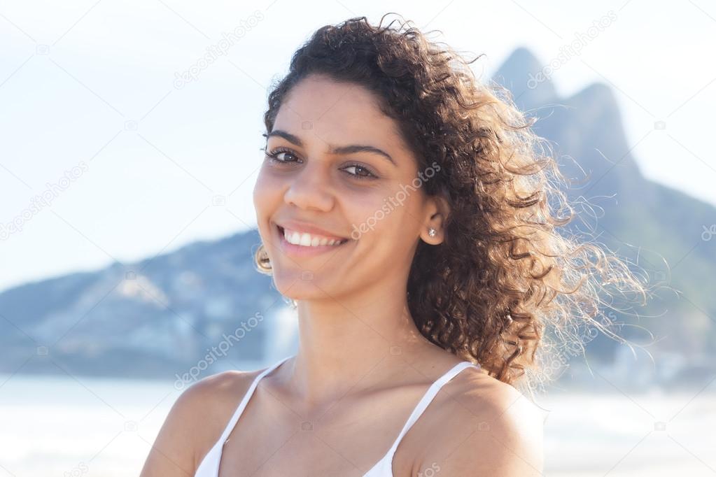 Laughing latin woman with curly hair at beach at Rio de Janeiro