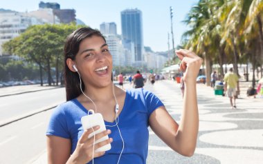 Dancing latin woman listening to music with phone clipart