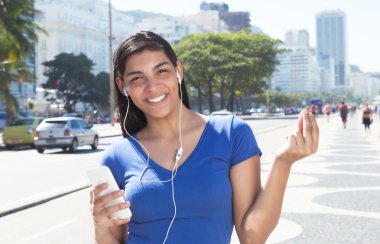 Beautiful latin woman listening to music with phone clipart