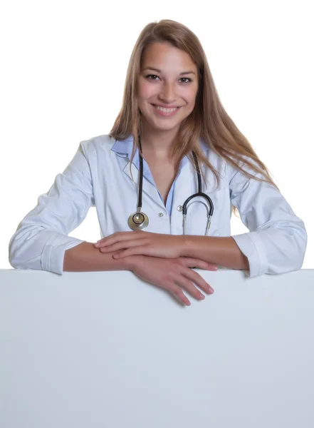 Young caucasian female doctor behind a blank board — Stock Photo, Image