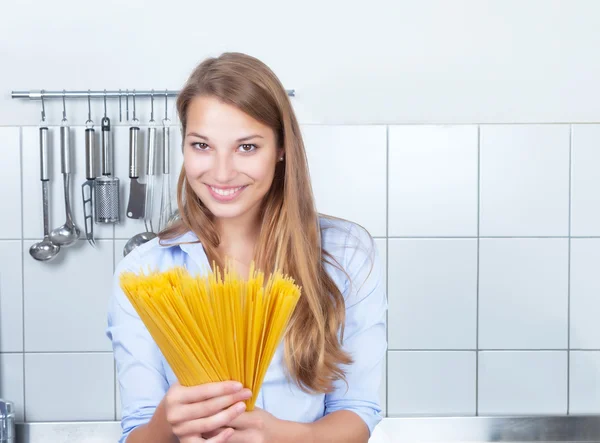 Riendo mujer rubia con espaguetis en la cocina — Foto de Stock