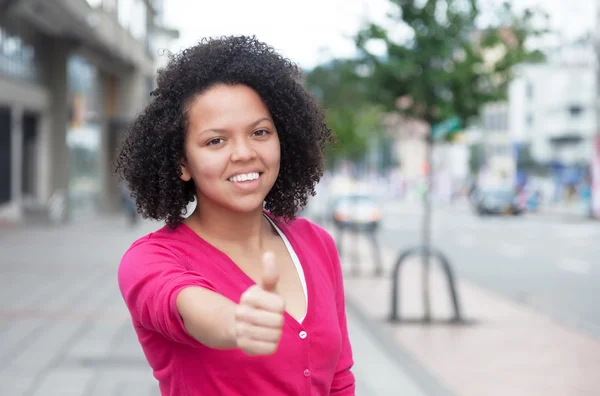 Africano mulher americana em camisa rosa mostrando polegar na cidade — Fotografia de Stock