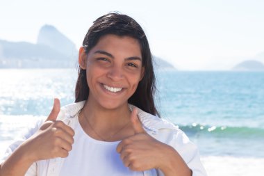 Her iki başparmak gösterilen Latin kadın Rio, uzun siyah saçlı