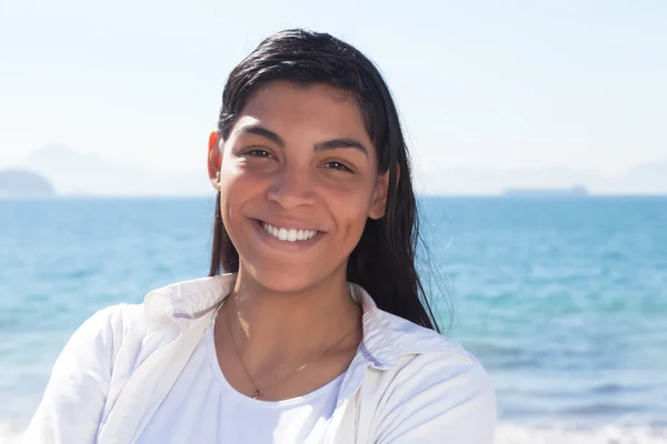 Donna latina ridente con lunghi capelli scuri in spiaggia — Foto Stock