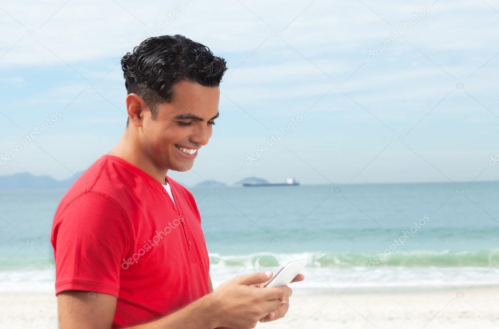Latin guy in red shirt looking at phone