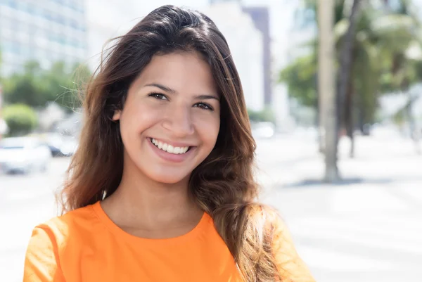 Kaunis valkoihoinen nainen oranssissa paidassa kaupungissa — kuvapankkivalokuva
