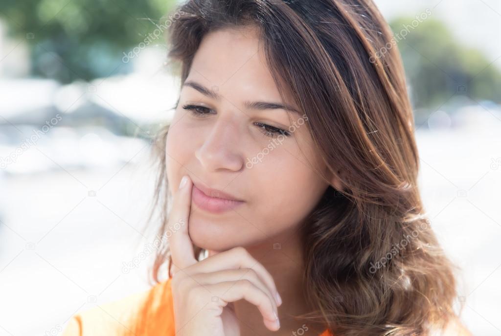 Thinking caucasian woman in a orange shirt