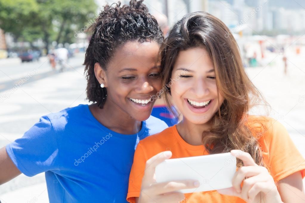African american and caucasian looking at phone