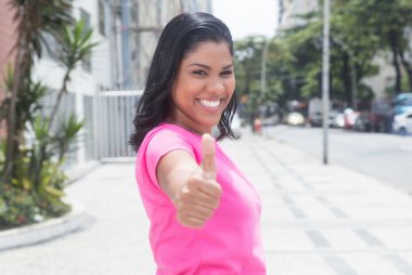 Pembe gömlekli başparmak şehirde gösterilen yerli latin kadın