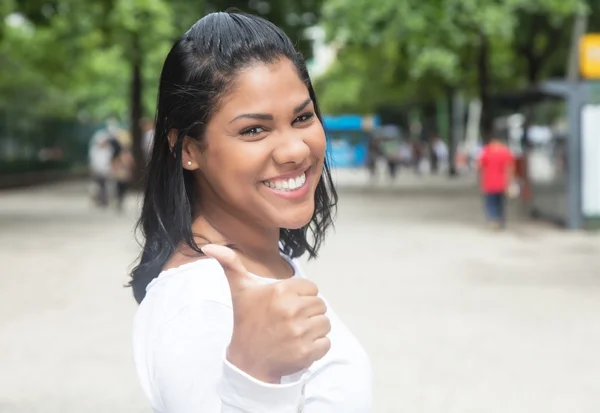 Mujer latina nativa con una camisa blanca que muestra el pulgar en la ciudad —  Fotos de Stock