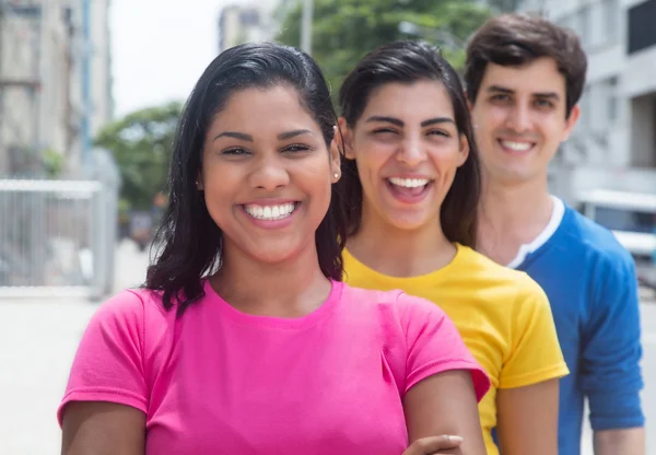 Group of three young people in colorful shirts standing in line — Stock Photo, Image