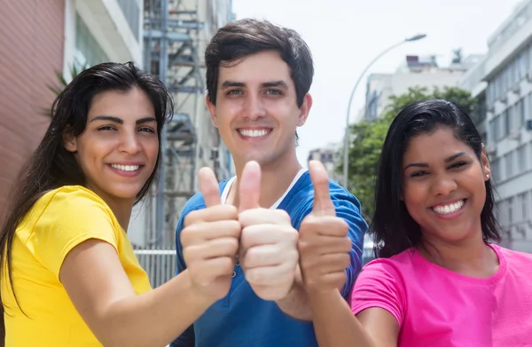 Group of three young people in colorful shirts showing thumbs — Stock Photo, Image