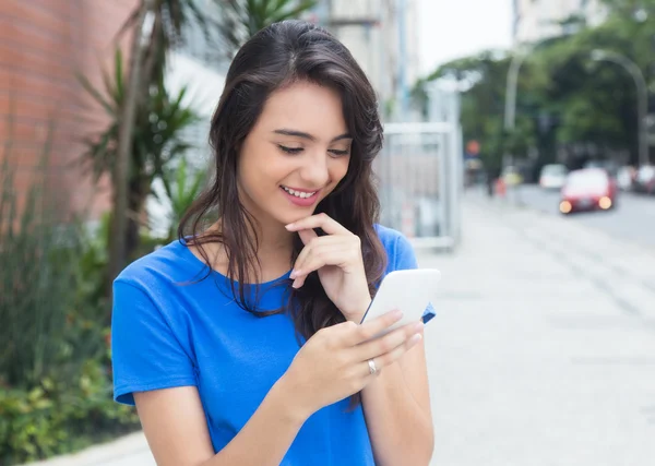 Mujer hermosa chica con camisa azul escribiendo mensaje en el teléfono — Foto de Stock