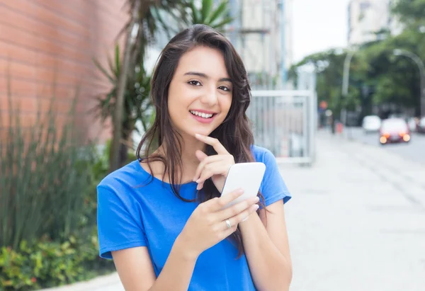 Riendo chica caucásica con camisa azul escribiendo mensaje en el teléfono — Foto de Stock