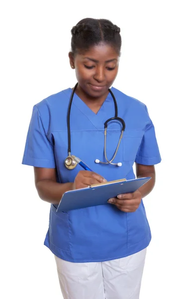 African nurse with clipboard writing message — Stock Photo, Image