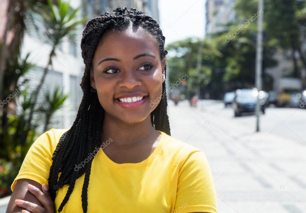 African american woman in a yellow shirt in city looking sideway