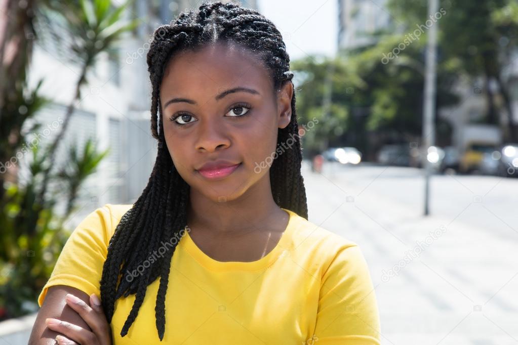 Smiling african american woman in a yellow shirt in the city