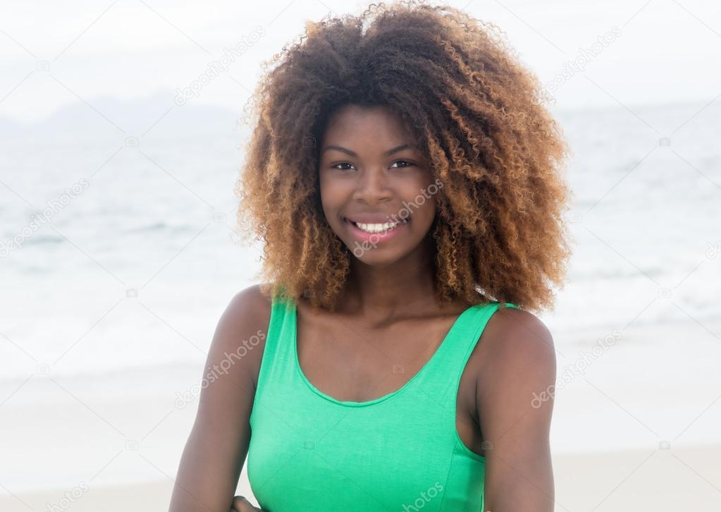 Happy brazilian girl in a green dress with crazy hairstyle