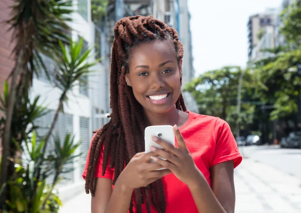 African woman with dreadlocks sending message in the city — Stock Photo, Image