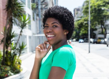 Happy african woman in a green shirt in the city clipart