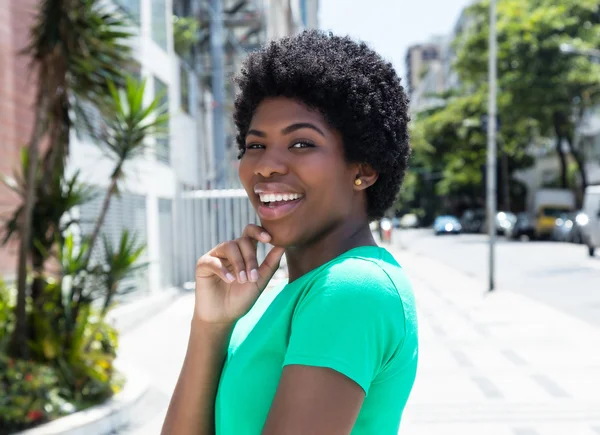 Mujer africana feliz en una camisa verde en la ciudad —  Fotos de Stock