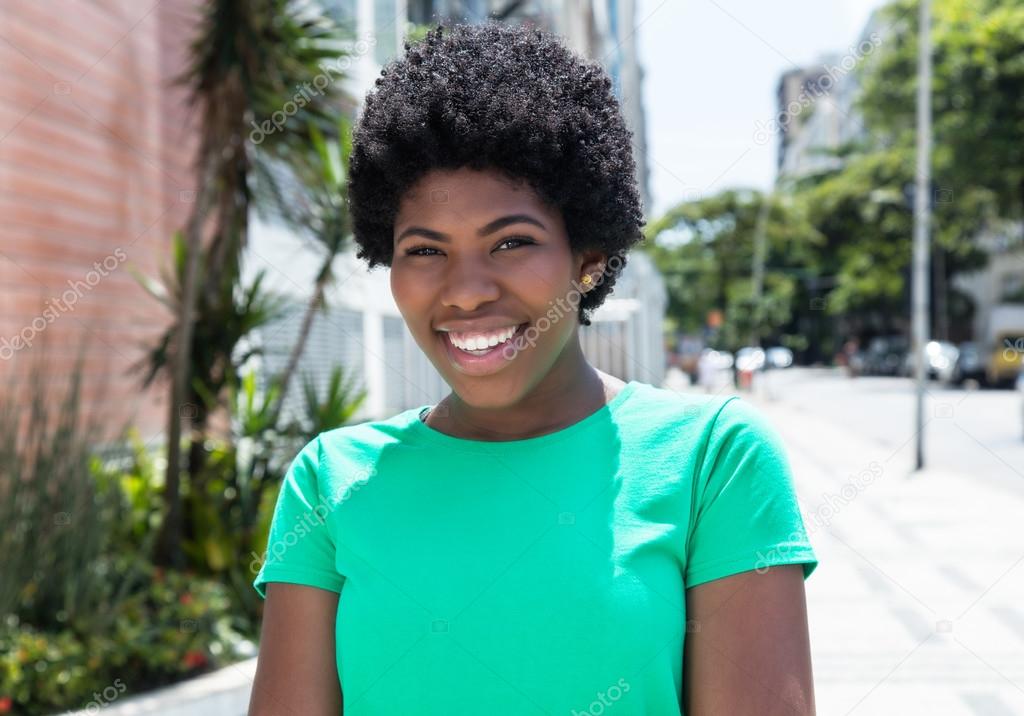 Laughing african woman in a green shirt in the city