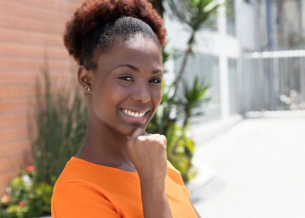 Mujer africana feliz en una camisa naranja —  Fotos de Stock
