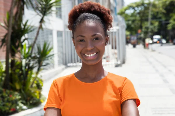 Beautiful african woman in a orange shirt — Stock Photo, Image