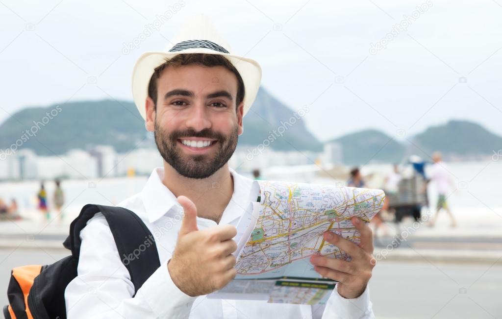Tourist with map at Rio de Janeiro showing thumb up