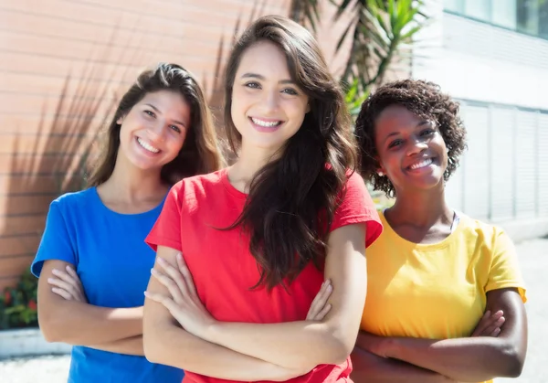 Three caucasian and african american girlfriends in colorful shi — Stock Photo, Image