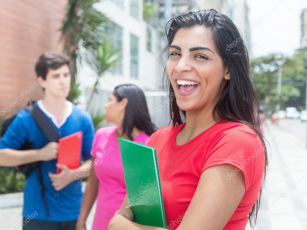 Laughing latin student in a red shirt with friends