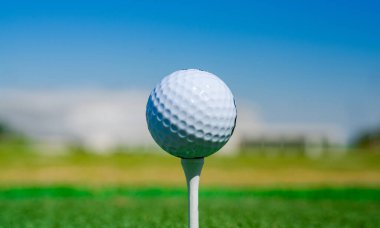 Golf sahasında golf topu gün batımında bulanık yeşil bir arazide. Bulanık yeşil bir saha üzerinde golf topu.
