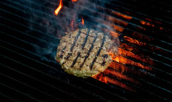 cooking burgers patty on hot grill with flames. Burger preparation