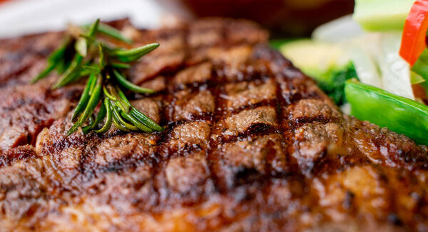 Close up view on serving of marinated grilled rib eye steak with baked potatoes and vegetables. rib eye steak