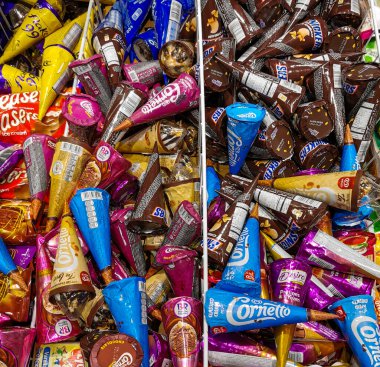 Bir süpermarkette dondurmanın farklı markaları ve tatları buzdolabı raflarına istiflenmiş. Muazzam Cam Kapı Dondurucu Koridoru. Bir paket dondurmalı şeker.